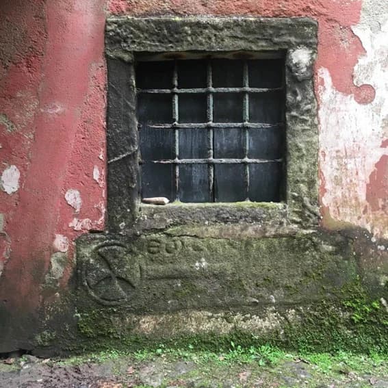 A weathered window in the old façade, its stone sill carved with a lost inscription