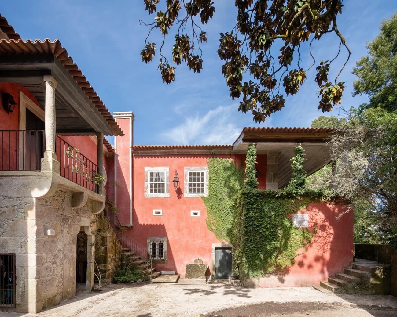 The red house today, its terrace and balcony restored beneath the magnolia branches