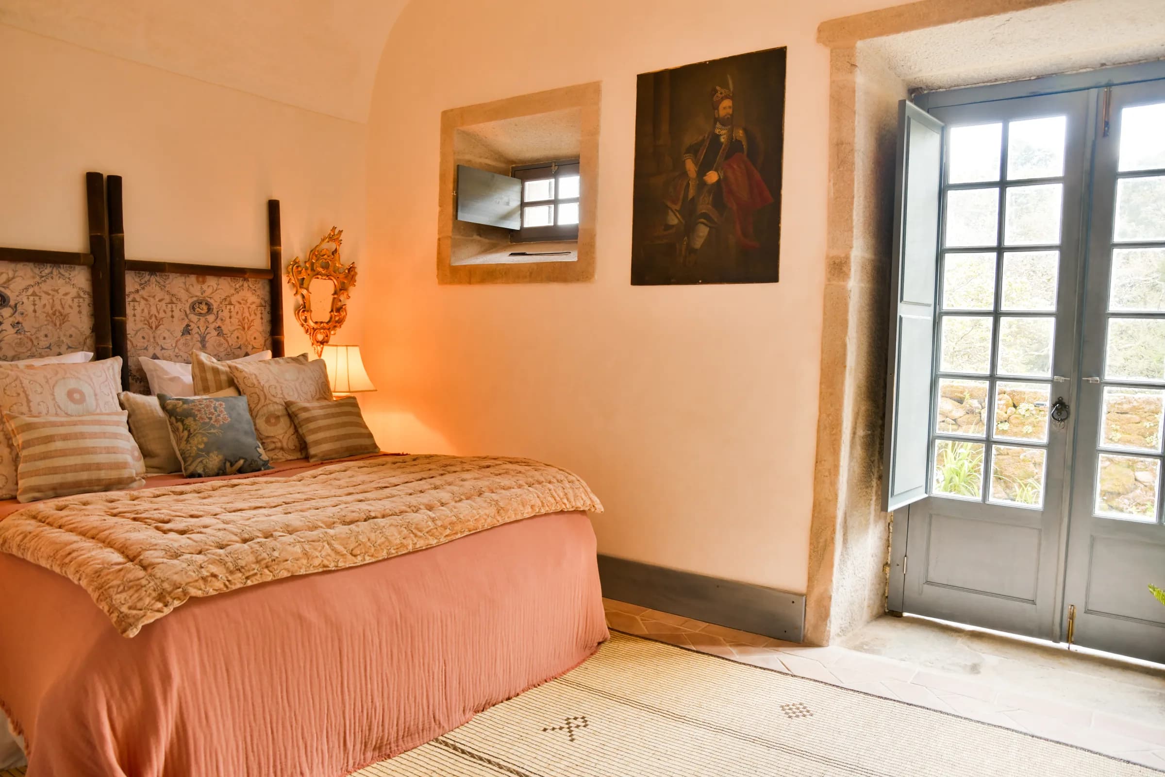 The Azalee suite — the bed dressed in terracotta, French doors beyond
