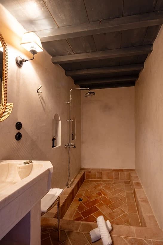 The Azalee bathroom — the rainshower and herringbone terracotta floor beneath a beamed ceiling
