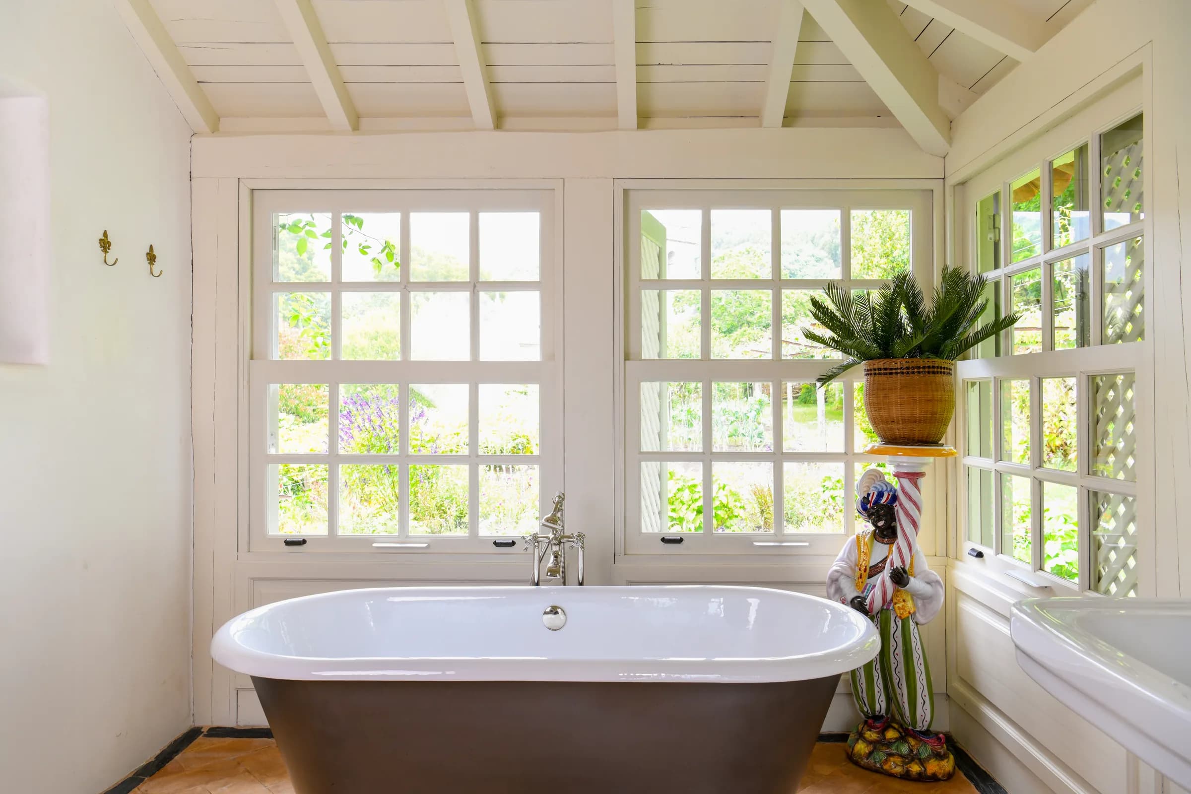 The Capucine bathroom — a freestanding tub beneath garden windows, the church tower beyond