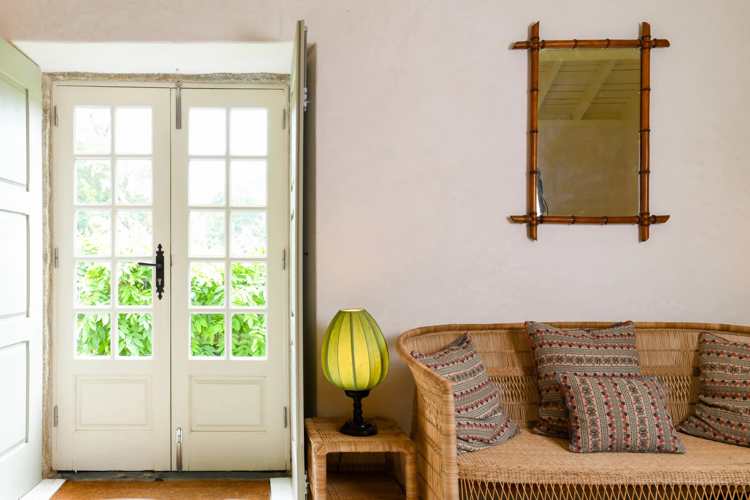 The Capucine cottage — French doors and a rattan bench in the sitting room