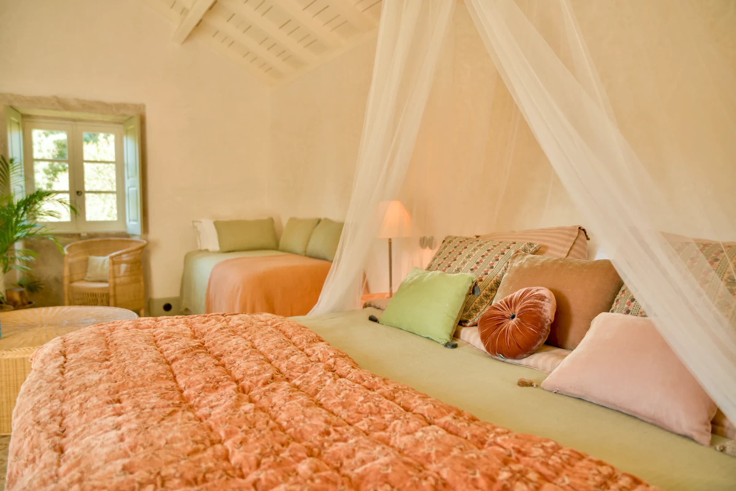The Capucine suite — the bed dressed in coral beneath sheer curtains