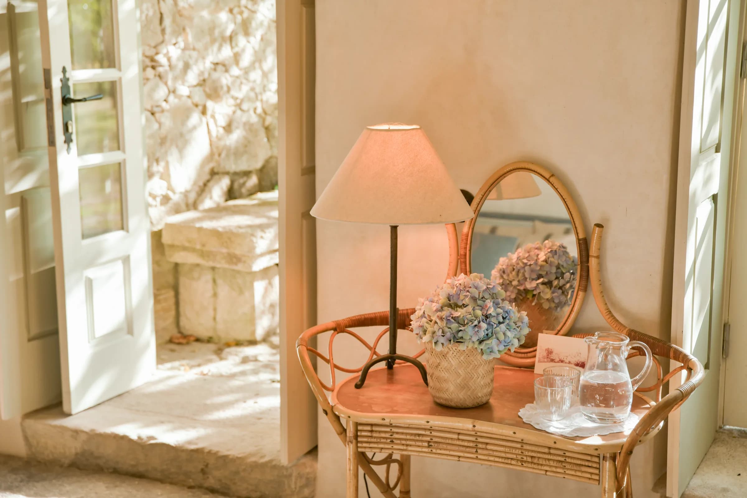 The Hortensia cottage — hydrangeas and an oval mirror on the rattan console