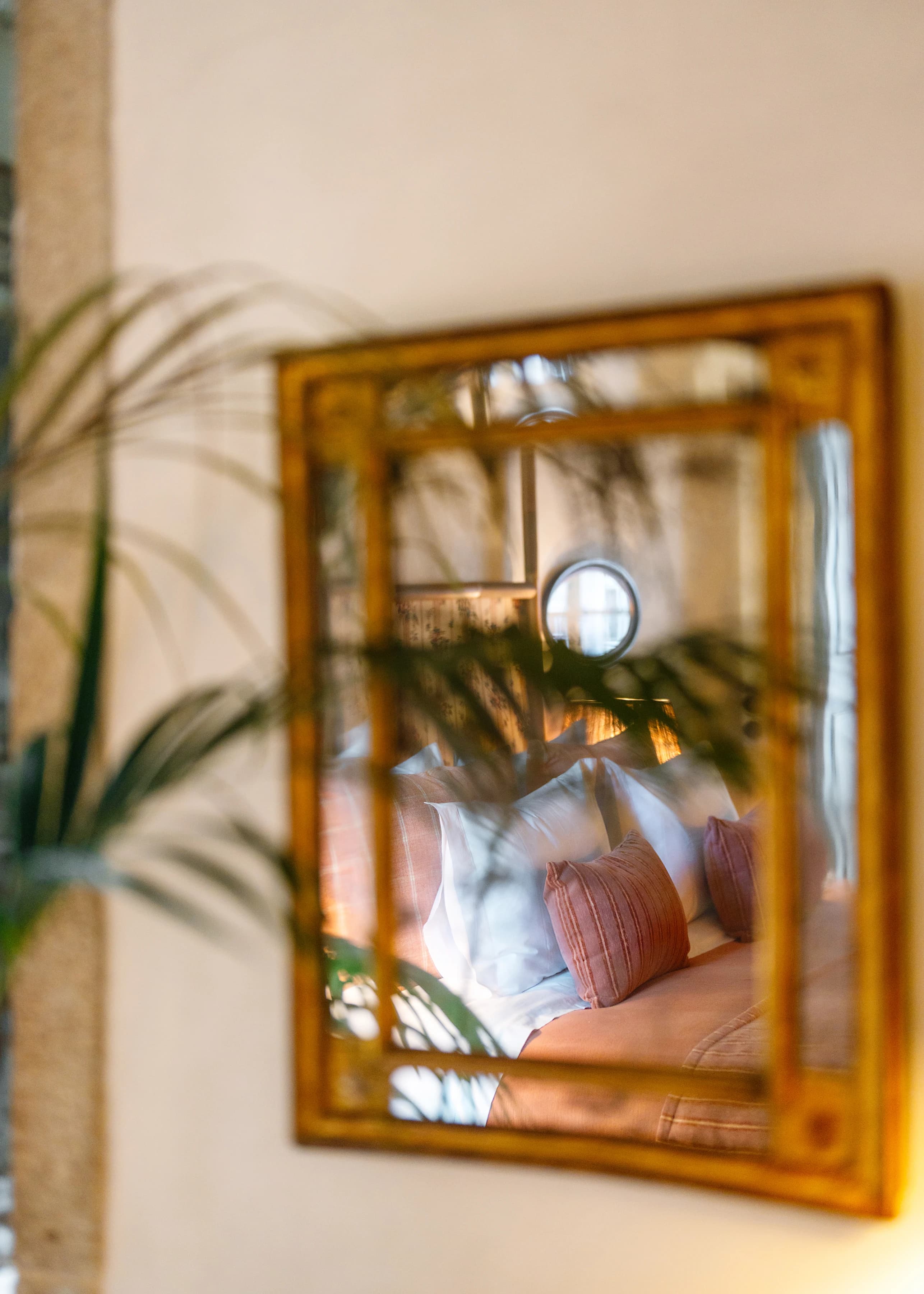 The Lilas suite — the bed reflected in an antique gilt-framed mirror, foliage in the foreground