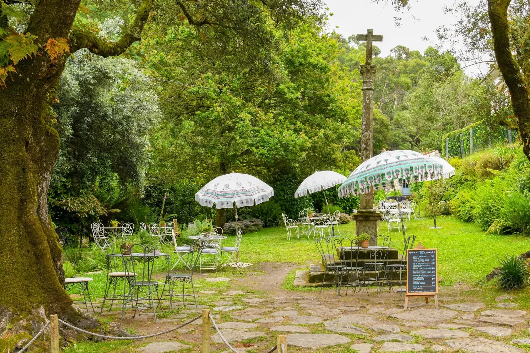 The stone wayside cross in the Café garden, on the Camino de Santiago, beneath old trees
