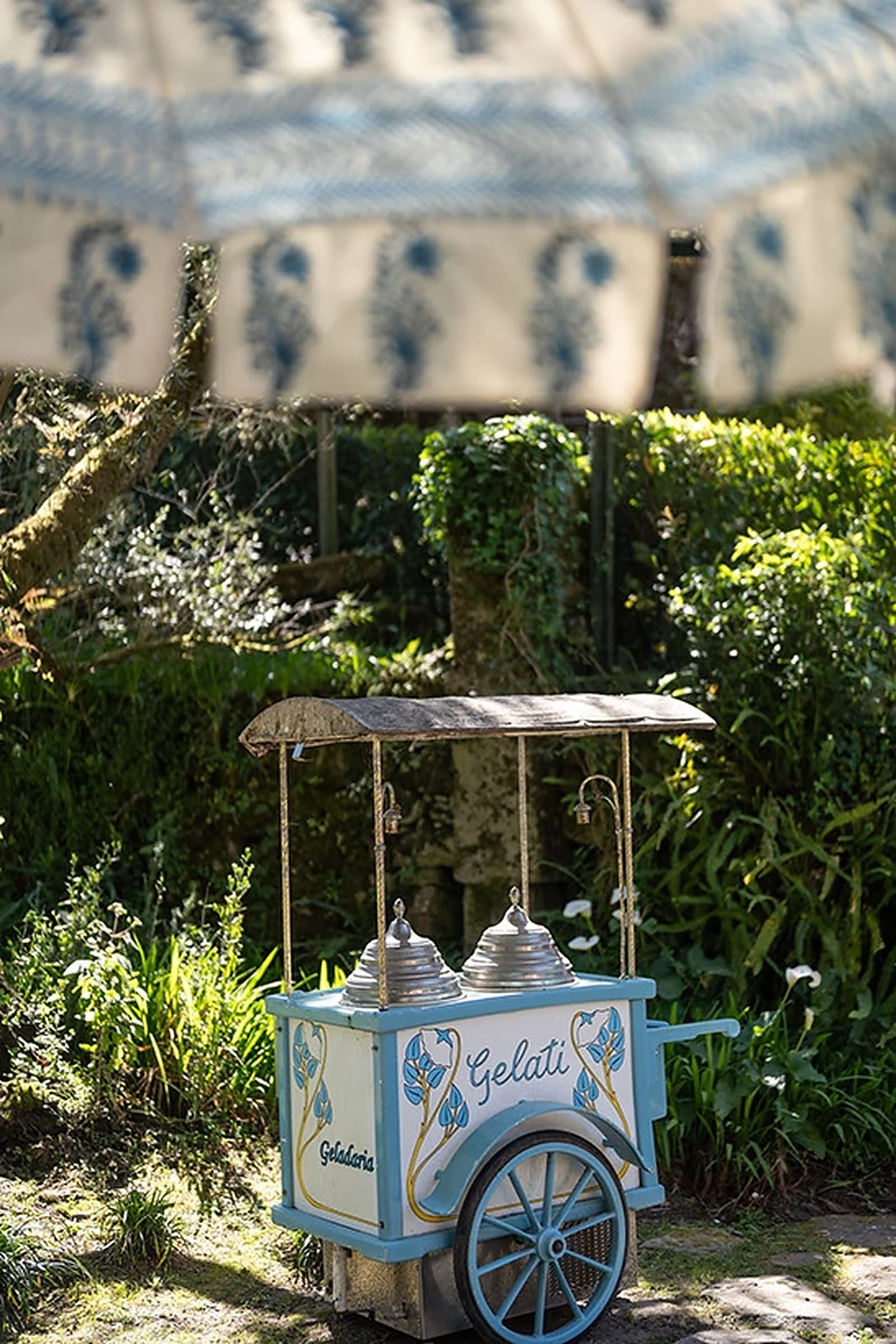 Une charrette à glaces d'époque dans le jardin, sous un parasol rayé
