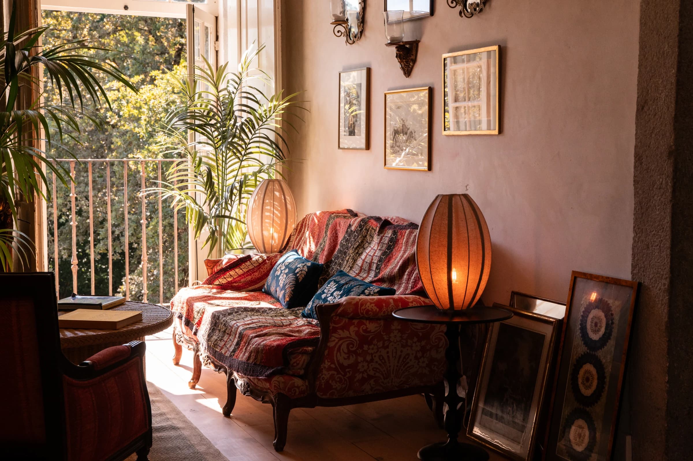 A sitting corner with kilim-draped sofa and paper lanterns, framed art on the wall