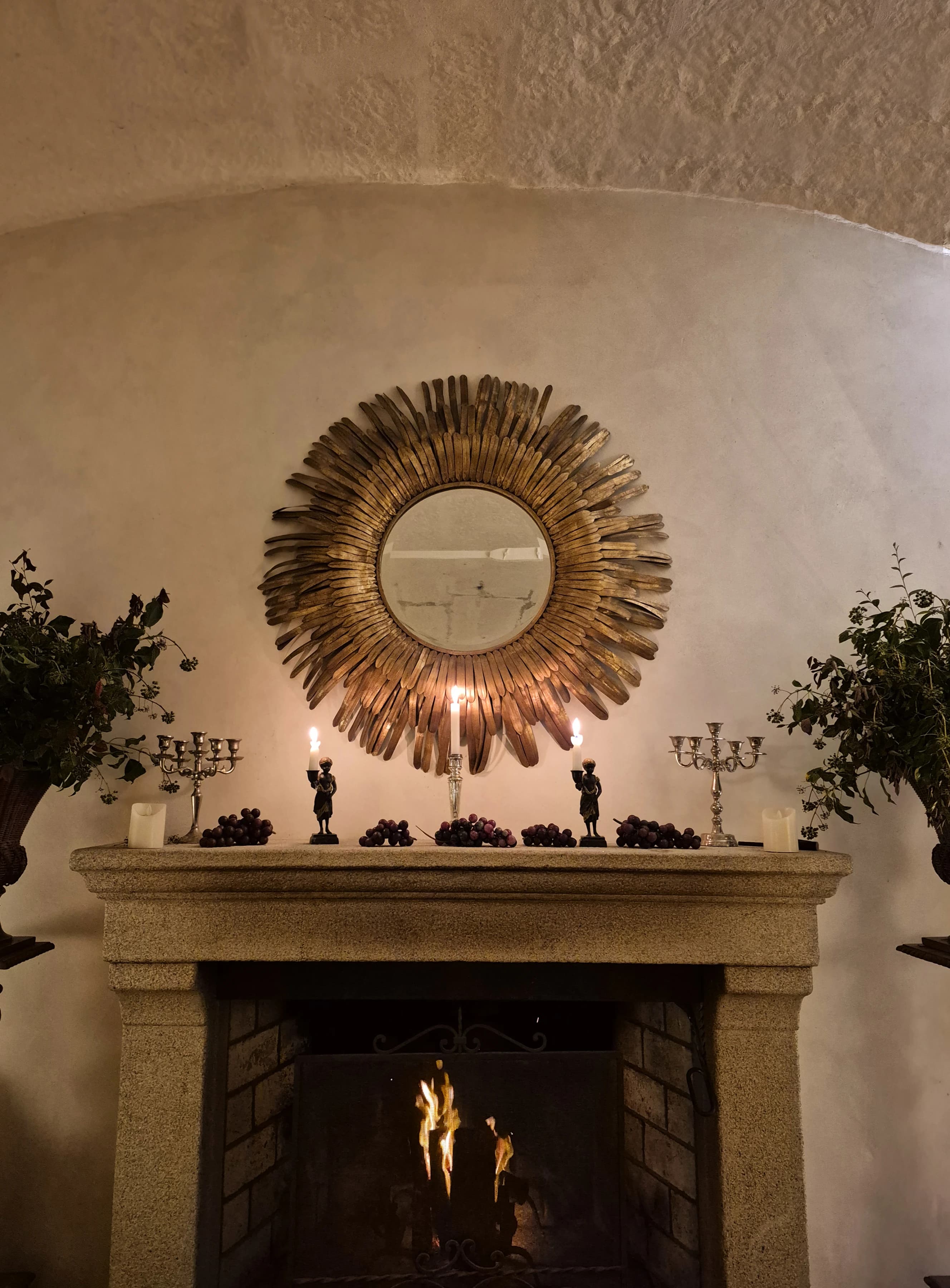The Magnolia fireplace, a gilt sunburst mirror above, candles and silver candelabras among grapes on the mantel