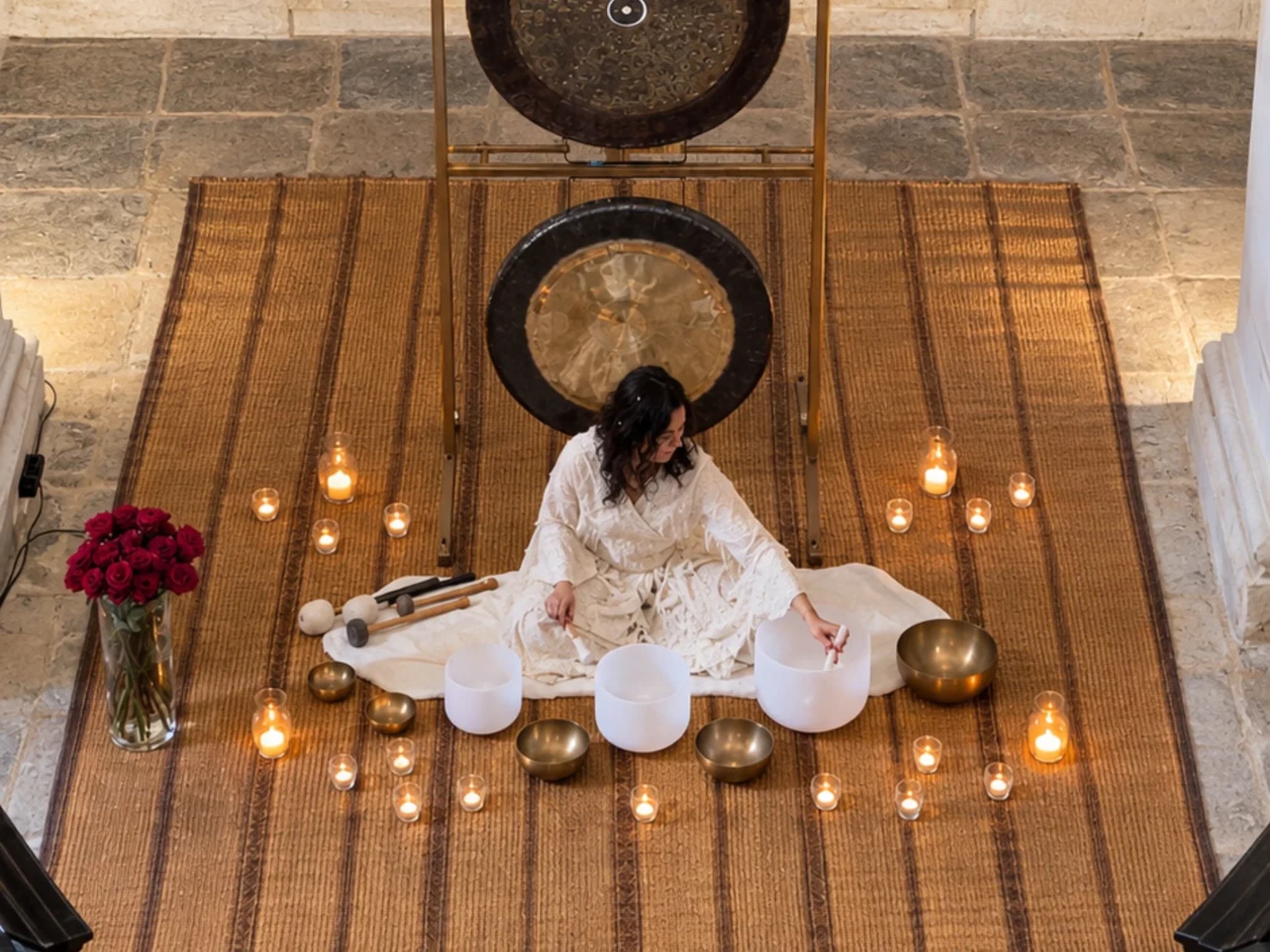 A sound bath laid out before the church altar, singing bowls and gongs on a woven mat