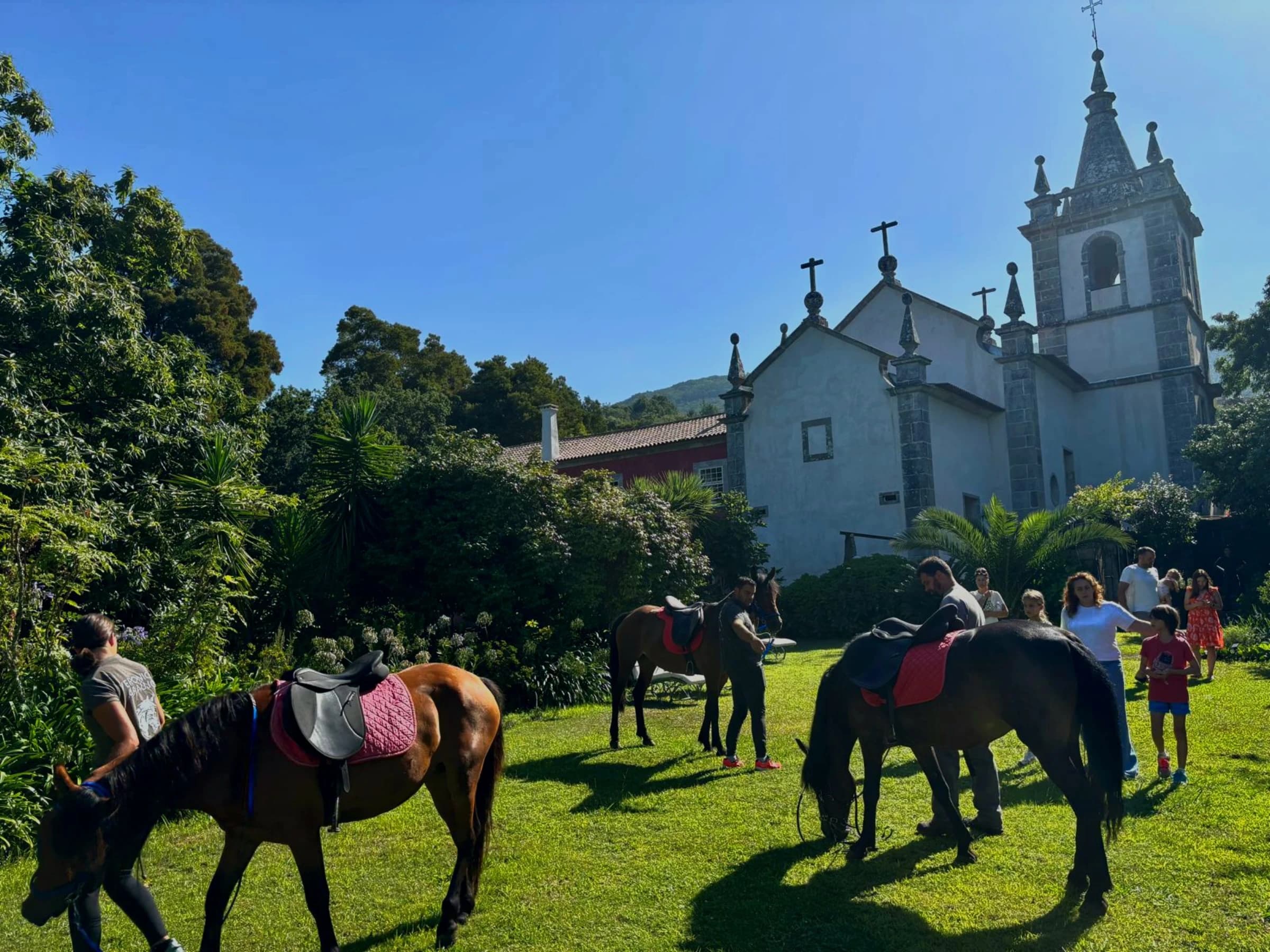 Guests on horseback in the gardens, the estate church behind them
