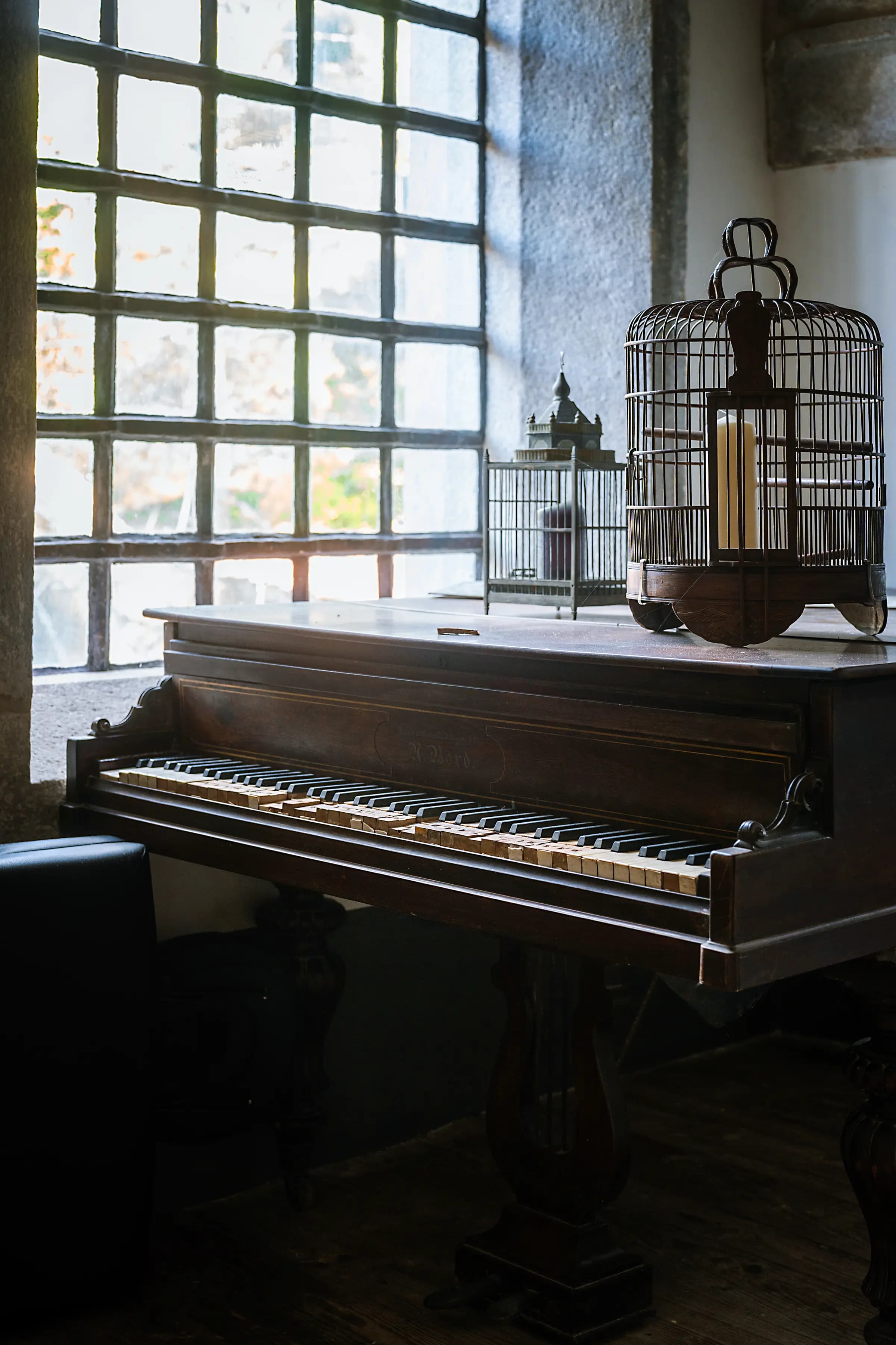 The grand piano and antique birdcage by the salon window